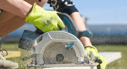 High school student using circular saw to cut wood