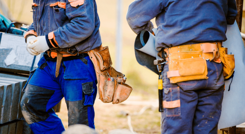 Two construction workers on jobsite wearing toolbelts