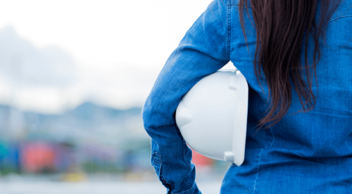 Woman construction worker holding white hardhat under her arm