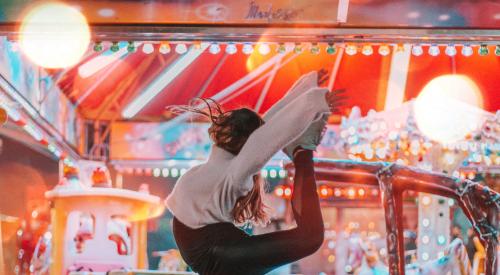 Gen Z woman leaping for joy in the air at carnival