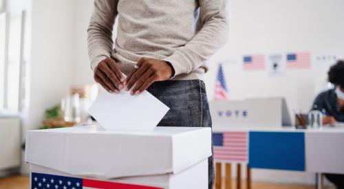 Voter placing ballot into box at voting location 