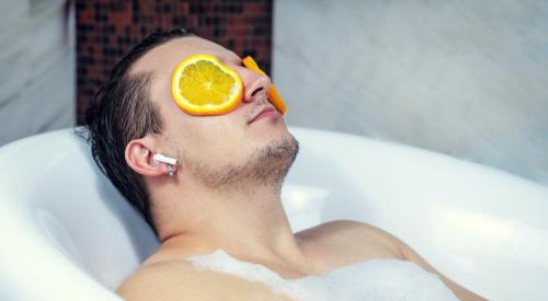 Man in sap bath tub with orange slices on his eyes