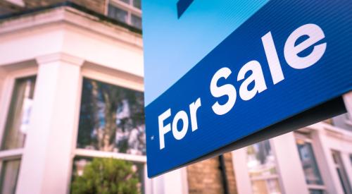 Blue 'for-sale' sign outside of residential home