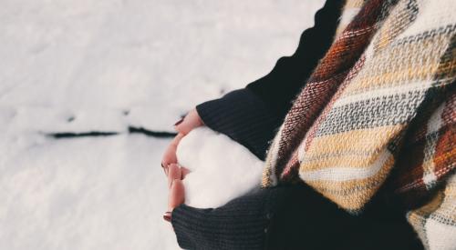 Person holding heart-shaped snowball