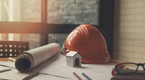 Home builder desk with floor plans and orange hard hat