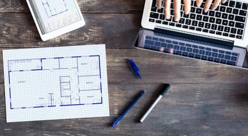 Builder working on computer with paper floor plans