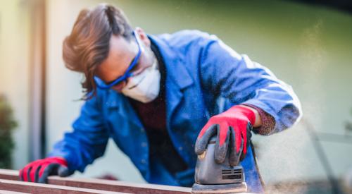 builder sanding down wood with mask