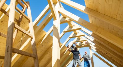 Builders in wood framed attic working on roof