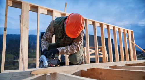 Builder using circular saw to cut timber framing for building a new home