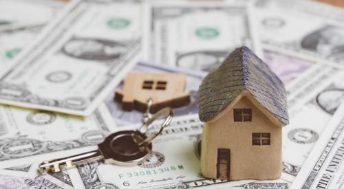 Small wooden home and keys on pile of money