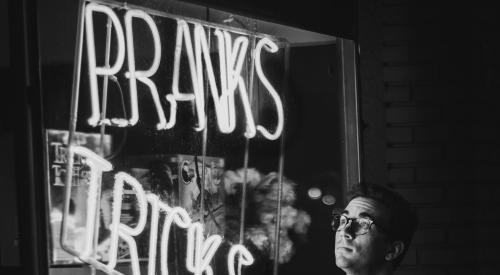 Man looking at neon sign in shop window