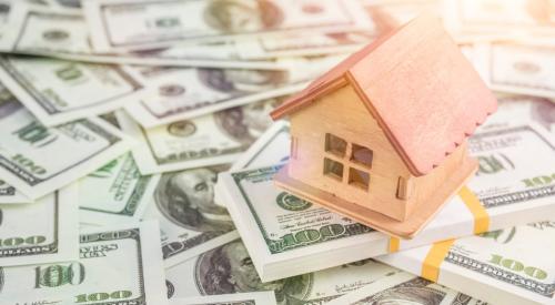 Small model house on top of pile of money