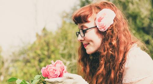 Woman smelling a rose in her garden enjoying the outdoors