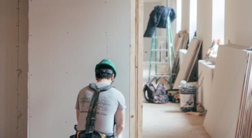 Construction worker at work on home interior installing drywall