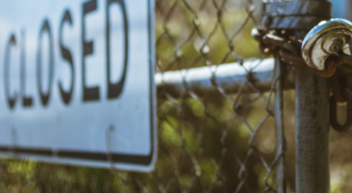 sign on construction jobsite with padlocked gate says "closed"