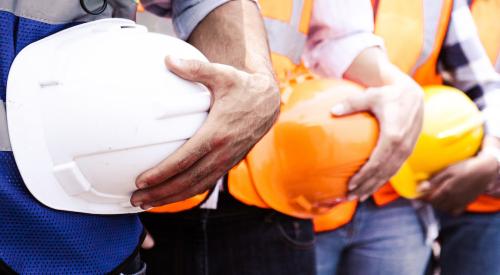 Row of construction workers holding hard hats