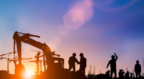 Construction crew against sunset sky