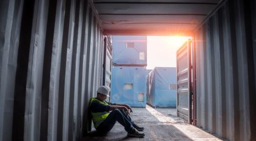 Isolated construction worker sitting and looking exhausted