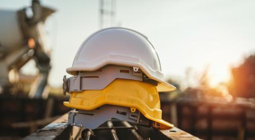 White and yellow construction hard hats stacked on top of each other on construction site