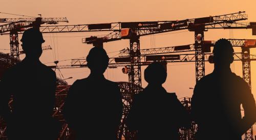 Shadows of construction workers against sunset on job site