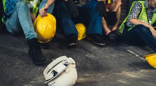 White hard hat on ground next to group of construction workers sitting down