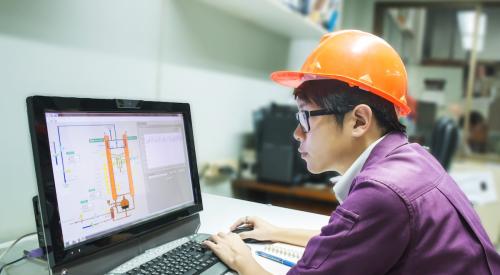 Construction student with hard hat working on computer