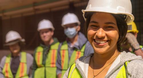 Young high school students in hard hats and reflective construction vests