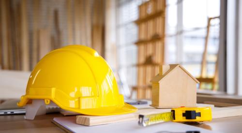 Construction hard hat next to tiny house model and tools