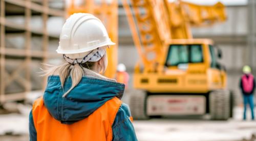 Woman in white construction hard hat and orange vest