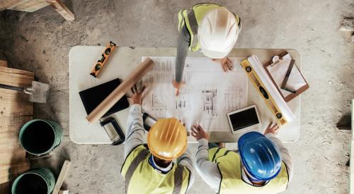 Construction workers in hard hats looking at house plans