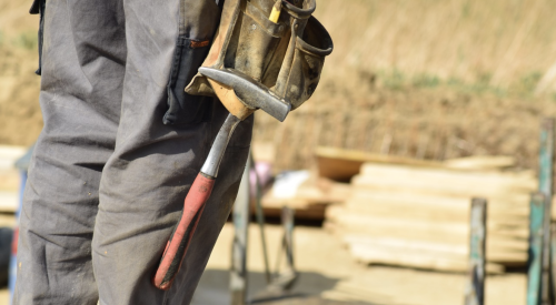 construction worker on jobsite with toolbelt and hammer ready