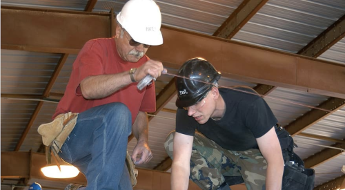 Construction worker training a younger worker on the jobsite