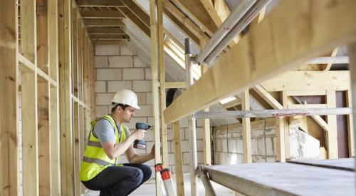 construction worker using drill on timber framing members