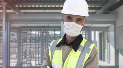 Happy construction worker on jobsite wearing protective facemask