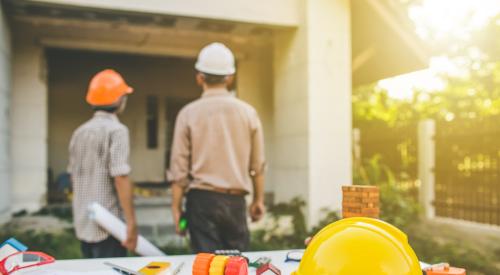 Contractors in hard hats standing outside of residential build