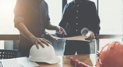 construction hard hats on table with computer and phone