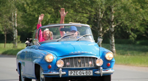 Couple in car driving away and waving good-bye