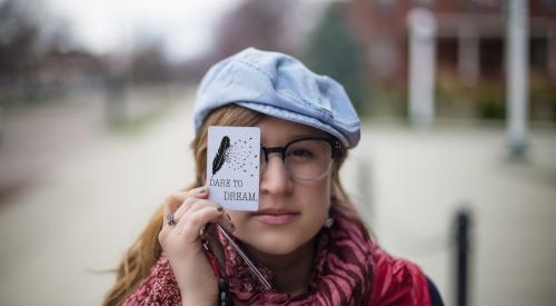 Woman with printed quote held up in front of face