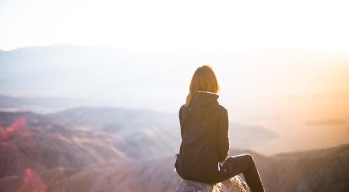 Woman sitting on a peak in mountains