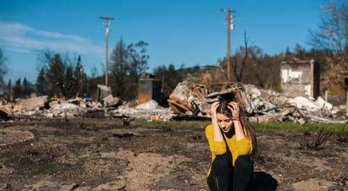 Woman at disaster site with hands on head