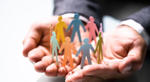 Businessman holding paper cutouts of small colorful figures