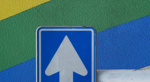 Up arrow sign against rainbow cement wall