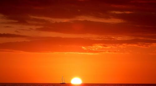 Sunrise with boat on the horizon on the ocean