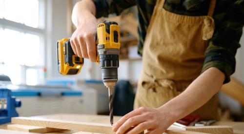 High school student drilling in wood shop class