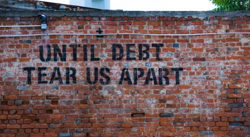 Mural 'until debt tear us apart' on brick wall