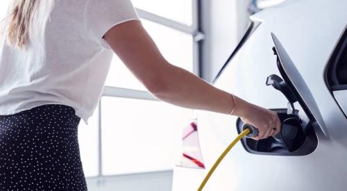 Woman charging electric vehicle at home