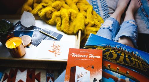 Woman with books and vinyl album and candle nearby