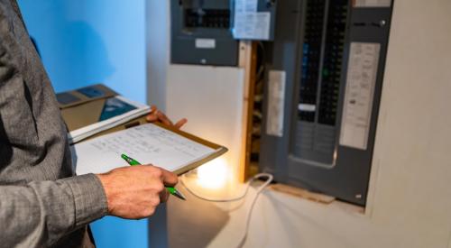 Inspector looking at power board in home