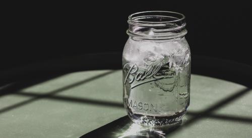 Mason jar with ice water in it on table