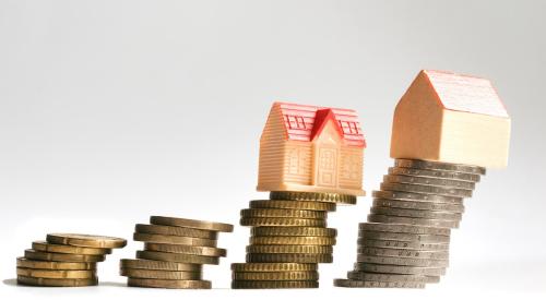 Houses stacked on coins leaning to the right